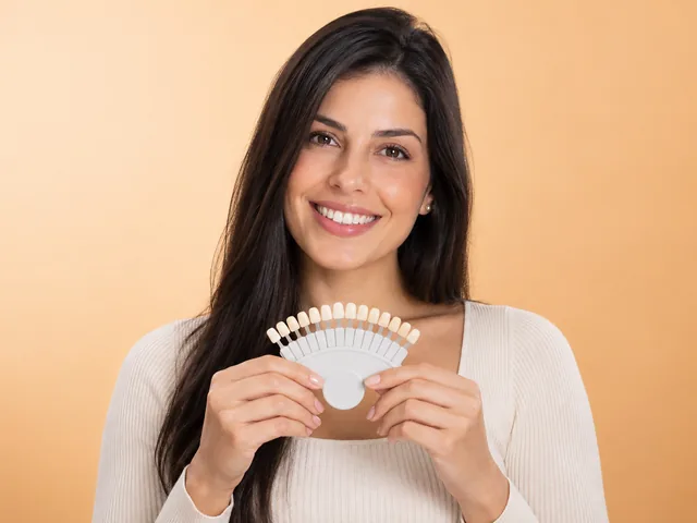 Imagem ilustrativa: mulher sorrindo segurando uma escala de cores dental